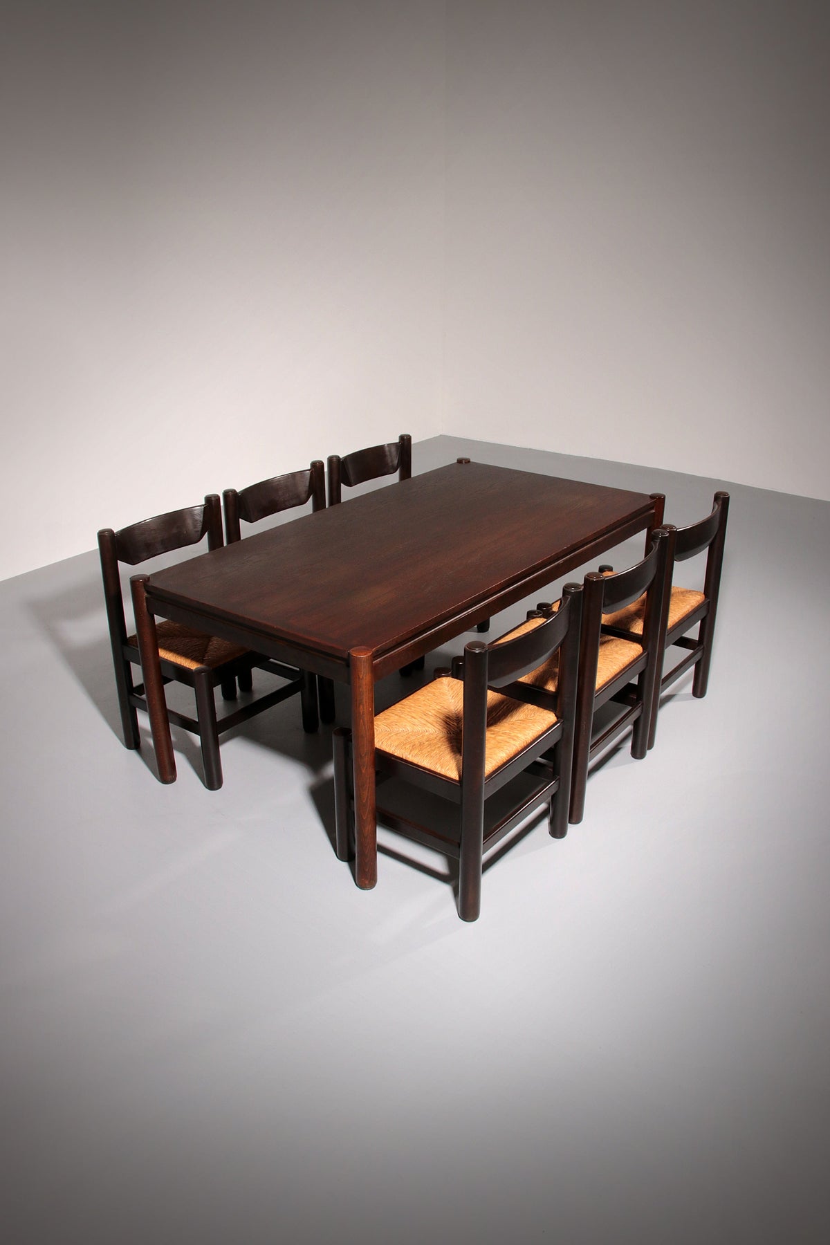 Eethoek geïnspireerd op Vico Magistretti, met zes elegant opnieuw gevlochten stoelen en een tafel.