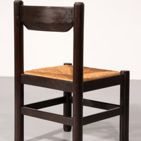 Eethoek geïnspireerd op Vico Magistretti, met zes elegant opnieuw gevlochten stoelen en een tafel.