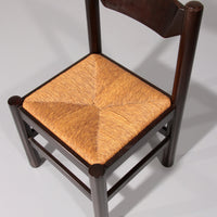 Eethoek geïnspireerd op Vico Magistretti, met zes elegant opnieuw gevlochten stoelen en een tafel.